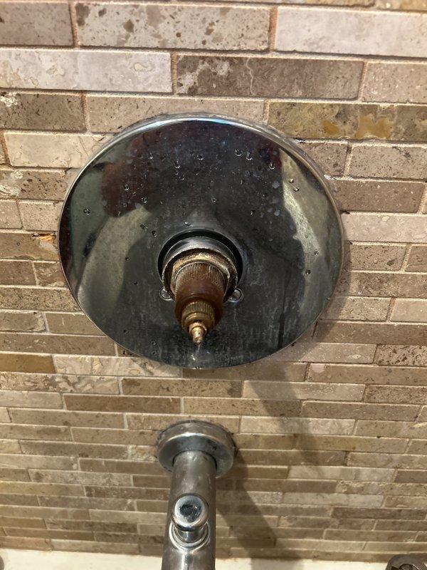 Responded to service call for broken and stripped shower handle. Upon inspection, found the shower valve stem exposed with the handle completely broken off the valve body. The existing trim plate showed significant age and water damage. Documented the condition of the fixture mounted on the brick wall and provided estimate for replacement shower handle and trim components to restore proper function to the shower control valve.