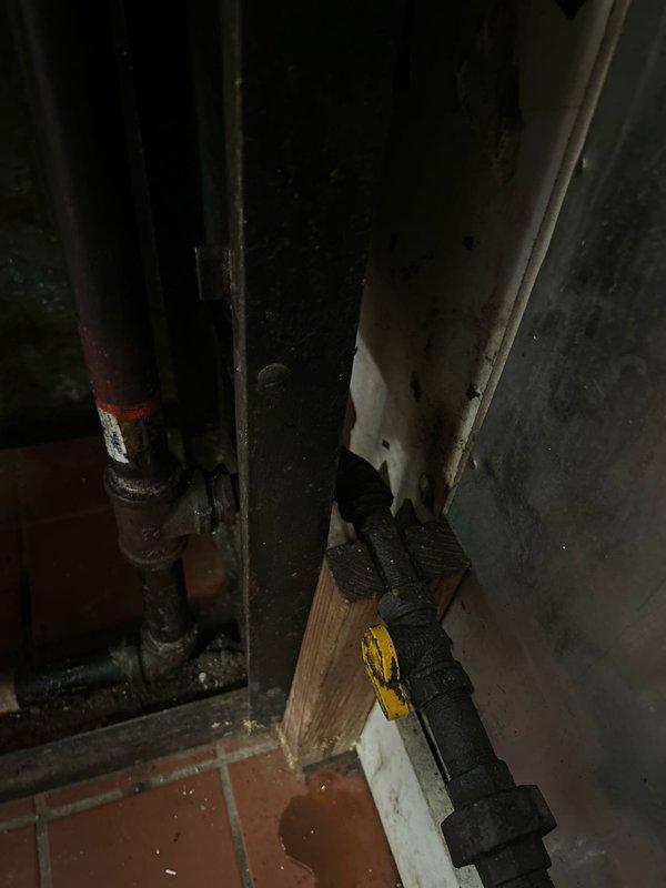 Conducted comprehensive gas piping estimate inspection in basement mechanical space and floor joist cavity. Assessed existing dark metal gas line infrastructure, documented current piping configuration including vertical and horizontal runs, and evaluated structural access points through wooden joist spaces for potential new gas line installation or system modifications.