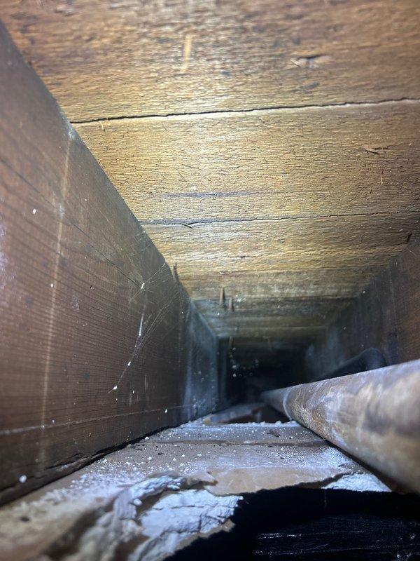 Conducted comprehensive gas piping estimate inspection in basement mechanical space and floor joist cavity. Assessed existing dark metal gas line infrastructure, documented current piping configuration including vertical and horizontal runs, and evaluated structural access points through wooden joist spaces for potential new gas line installation or system modifications.