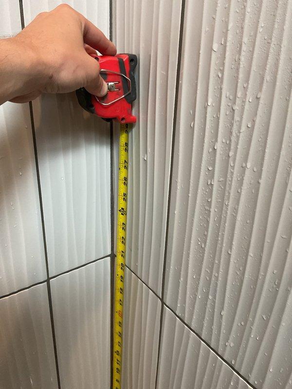 Responded to callback for leak following recent shower valve replacement. Upon inspection, discovered active water intrusion at shower enclosure with visible moisture accumulation on wall panels and surrounding surfaces. Performed diagnostic measurements to assess extent of leak and identify source. Documentation captured showing condensation pattern on corrugated metal ceiling components and moisture present on textured wall panels adjacent to shower valve installation area. Further investigation required to determine if leak originates from valve connection, supply lines, or shower arm penetration through wall assembly.