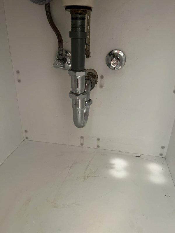 Installed new chrome P-trap assembly and drain components for bathroom vanity sink, including tailpiece with mounting flange and proper trap configuration. Replaced water supply line and verified all connections for proper drainage and leak-free operation under double vanity with marble countertop.