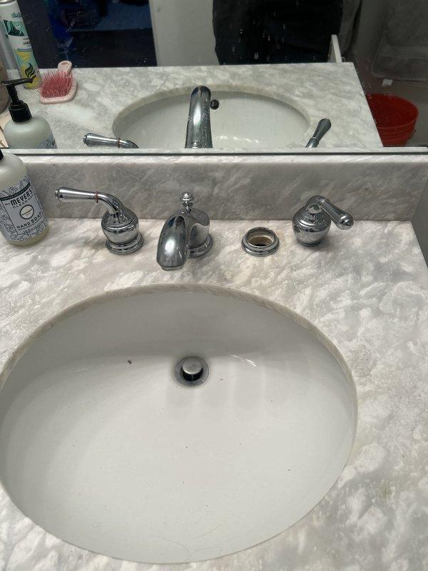 Installed new chrome P-trap assembly and drain components for bathroom vanity sink, including tailpiece with mounting flange and proper trap configuration. Replaced water supply line and verified all connections for proper drainage and leak-free operation under double vanity with marble countertop.