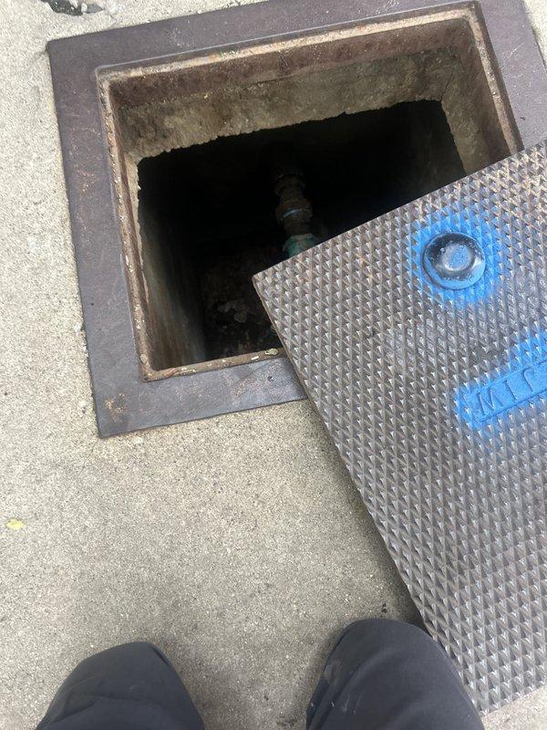 Completed plumbing estimate for water line valve replacement at underground utility vault access point. Inspection revealed corroded metal valve assembly connected to copper piping within confined mechanical compartment, with visible deterioration on vault frame and cover plate. Documented existing conditions including valve configuration, copper pipe routing, and surrounding infrastructure to provide accurate replacement specifications and labor assessment.