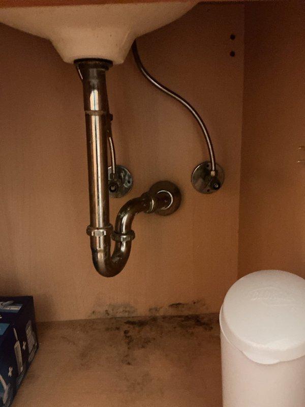 Responded to leaky faucet complaint in fifth-floor condo unit of thirteen-story residential high-rise. Upon inspection, assessed under-sink plumbing assembly including chrome P-trap, tailpiece, and supply lines with shut-off valves. Identified water damage and staining on cabinet floor indicating previous or ongoing leak. Tightened connections at drain assembly and supply line fittings, tested for leaks, and verified proper drainage function. Recommended monitoring cabinet area for additional moisture accumulation and potential replacement of deteriorated cabinet base materials if leaking persists.