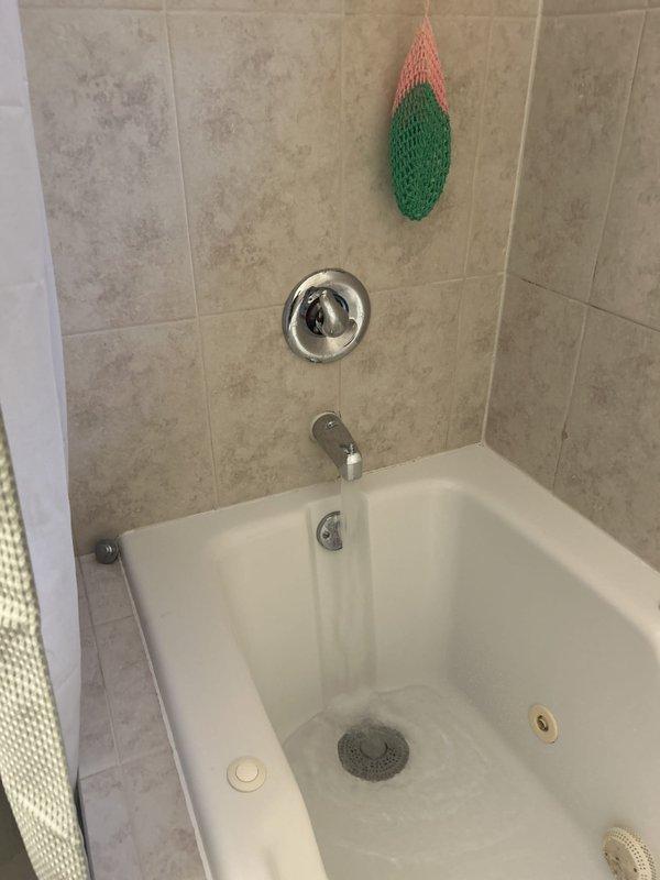 Responded to water leak complaint affecting downstairs area in 30-year-old residence. Conducted thorough leak inspection and traced source to bathroom plumbing system. Removed section of wall covering and drywall to access concealed piping behind bathtub enclosure, exposing structural framing and OSB sheathing. Located active leak in supply or drain lines servicing the tub/shower fixture assembly. Performed necessary repairs to compromised plumbing connections. Wall cavity left open for moisture monitoring and verification of repair effectiveness before reconstruction. Documented conditions with photos showing extent of access required and bathroom fixture configuration.