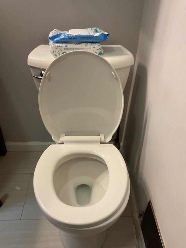 Responded to water leak complaint behind bathroom toilet in 90-year-old residence. Upon inspection, discovered deteriorated wax ring seal and corroded toilet flange causing water seepage onto floor. Removed toilet to access flange assembly, revealing significant rust buildup and wax ring failure. Replaced failed wax ring with new seal, cleaned and prepared flange mounting surface, and reinstalled toilet with proper seal compression. Verified no active leaks during testing and confirmed secure toilet mounting. Cleaned affected floor area and disposed of deteriorated components.