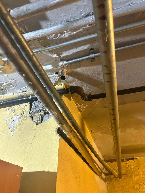Conducted plumbing estimate for gas range fixture and associated supply lines. Inspected existing copper gas piping infrastructure in basement utility area, noting multiple supply lines with age-appropriate patina and secure mounting to floor joists. Evaluated pipe routing, support brackets, and overall condition of gas distribution system. Assessed kitchen gas range connection point and verified appliance positioning relative to gas supply location. Examined white four-burner gas range with digital controls for proper installation clearances and ventilation requirements. Documented existing pipe configuration and structural elements to determine scope of work for fixture installation or modification.