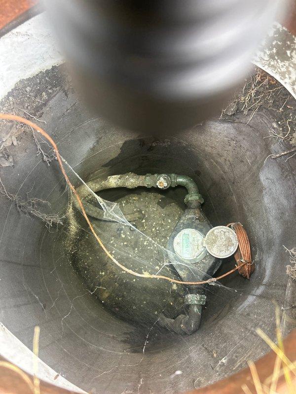 Conducted assessment of existing water service line that was not compliant with current plumbing codes. Evaluated the outdated piping system including a vertical copper pipe installation with ball valve in the basement utility area. Inspected the water service entry point, floor mounting connections, and associated drainage infrastructure including sump pit with pump components. Documented all existing conditions and code violations to prepare comprehensive estimate for complete water service line replacement with code-compliant materials and installation methods.