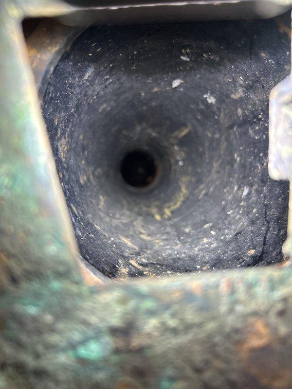 Responded to emergency drainage call at commercial facility experiencing recurring flooding issues. Upon arrival, conducted visual inspection of exterior drain system and identified floor drain with significant rust staining and water damage patterns indicating chronic drainage problems. Previous camera inspection by another plumber had confirmed sewer line misalignment requiring full line replacement. Performed assessment of drain opening revealing heavy buildup of debris, sediment accumulation, and severe corrosion on metal components. Documented existing conditions showing oxidation, green patina formation, and structural deterioration of drain infrastructure. Discussed immediate temporary remediation options with on-site management to mitigate flooding risk while facility plans comprehensive sewer line replacement project. Provided estimate for short-term drainage solutions to maintain operational functionality until permanent repairs can be scheduled and completed.