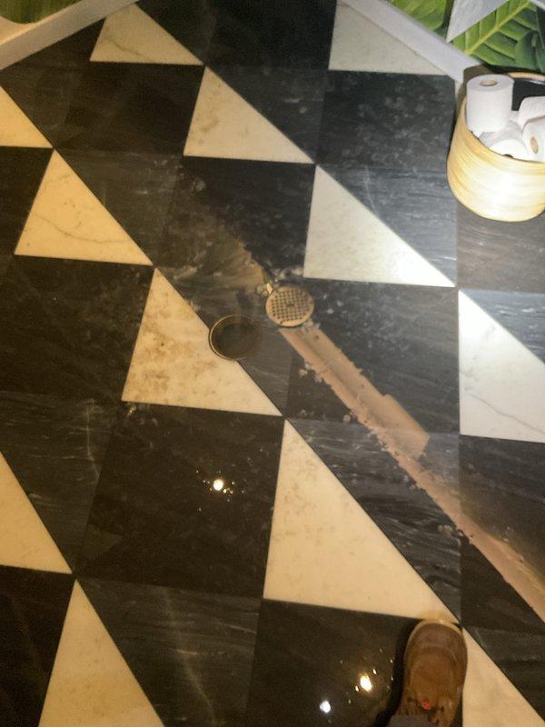 Responded to clogged floor drain in commercial space with decorative marble tile flooring. Accessed main water supply through wall-mounted utility panel to isolate affected drainage system. Inspected copper plumbing lines and water meter connections to verify proper flow and rule out supply-side complications. Cleared obstruction from floor drain grate, restoring proper drainage function. Verified system operation and confirmed no backup or overflow issues remained.