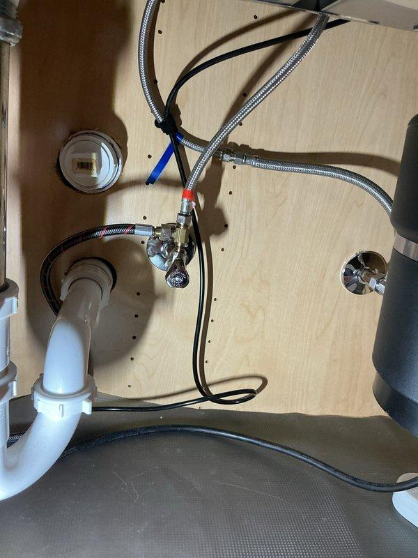 Responded to warranty callback for reported leak following previous service. Upon arrival, inspected kitchen sink installation and underneath cabinet plumbing connections. Verified all supply line connections, faucet mounting, and drain assembly for proper installation and potential leak sources. Cleaned and dried affected countertop area. All connections found secure with no active leaking observed during inspection. Photographed installation showing braided stainless steel supply lines, PVC drain connections, and faucet assembly for documentation purposes.