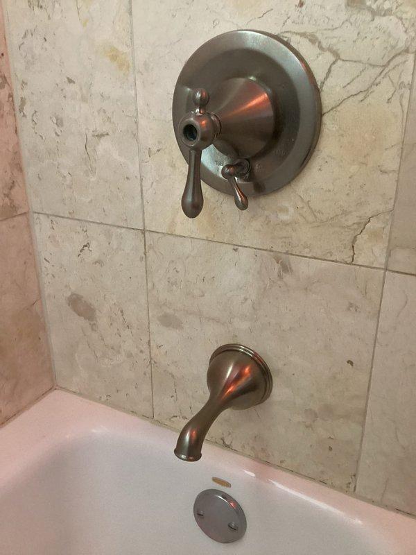 Completed plumbing repair service involving assessment and documentation of existing bathtub and shower fixture installation. Inspected copper supply lines, shower valve assembly with lever control, tub spout, and drain components mounted on tiled wall surface. Evaluated plumbing connections at wall penetration points and verified proper fixture alignment and functionality of the bathtub/shower combination system.