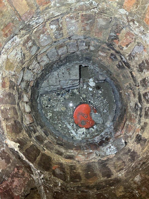 Responded to callback for garden unit experiencing water intrusion through floor. Conducted site assessment and documented conditions of existing drainage system, including brick-lined sump pit and floor drains in shower area. Photographed deteriorated brick shaft showing significant efflorescence, moisture damage, and compromised mortar joints, along with concrete floor surfaces exhibiting water staining and multiple drain points, to provide comprehensive documentation for drain tile system estimate.