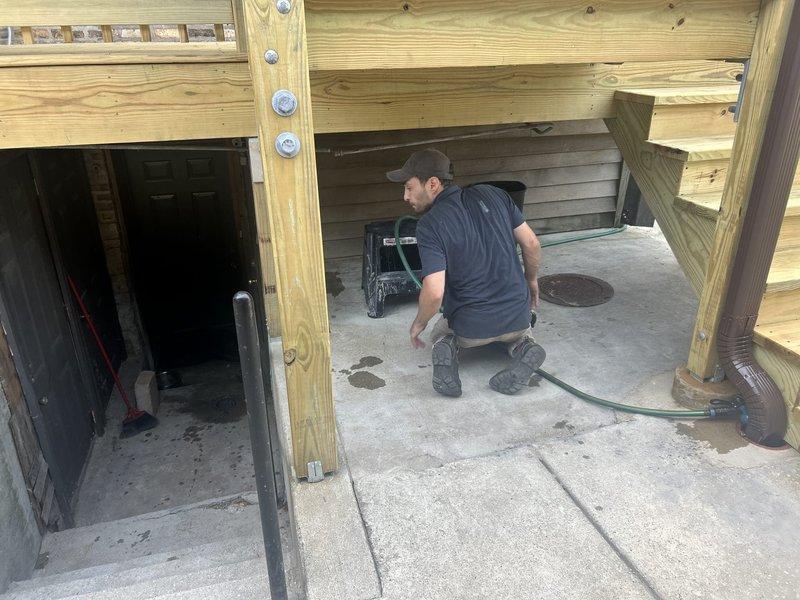 Responded to water intrusion complaint at residential property. Upon arrival, conducted thorough inspection of exterior deck structure and underlying drainage systems. Investigation revealed compromised drainage pipe beneath concrete paver deck surface, evidenced by significant mineral deposits, biological staining, and water damage visible within the pipe interior. The drainage system showed signs of long-term moisture exposure with yellowish-brown discoloration indicating chronic water flow issues. Accessed utility opening in deck surface to assess pipe condition and water infiltration pathways. Documented findings with photographic evidence showing extent of pipe deterioration and staining patterns consistent with improper drainage or backup conditions. The compromised drainage infrastructure was identified as the probable source of water entering the structure, with moisture likely migrating through deck foundation and into living spaces below.