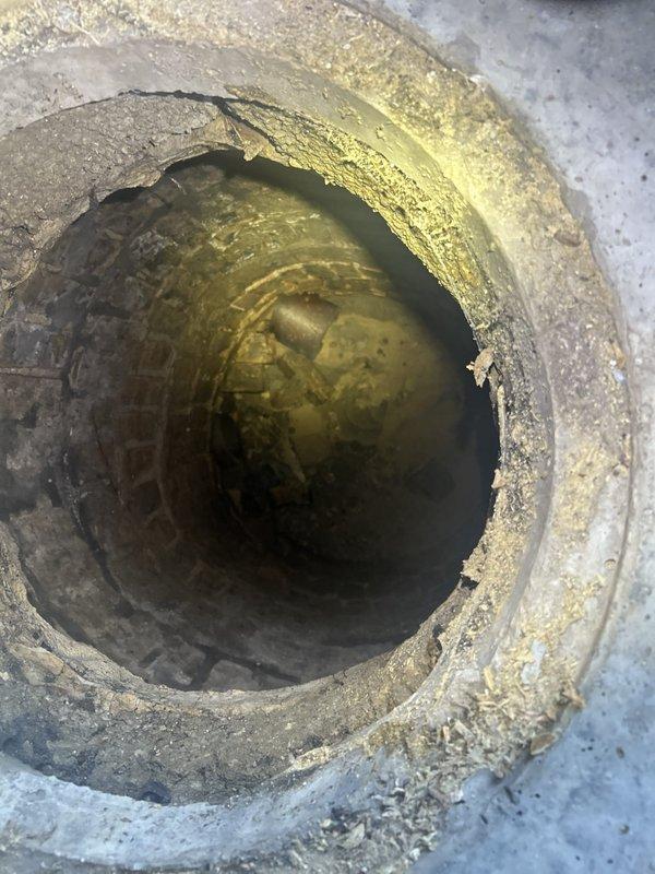 Responded to water intrusion complaint at residential property. Upon arrival, conducted thorough inspection of exterior deck structure and underlying drainage systems. Investigation revealed compromised drainage pipe beneath concrete paver deck surface, evidenced by significant mineral deposits, biological staining, and water damage visible within the pipe interior. The drainage system showed signs of long-term moisture exposure with yellowish-brown discoloration indicating chronic water flow issues. Accessed utility opening in deck surface to assess pipe condition and water infiltration pathways. Documented findings with photographic evidence showing extent of pipe deterioration and staining patterns consistent with improper drainage or backup conditions. The compromised drainage infrastructure was identified as the probable source of water entering the structure, with moisture likely migrating through deck foundation and into living spaces below.
