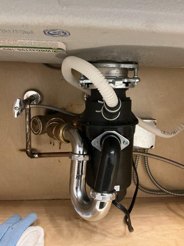 Responded to property inspection requirement for water heater system upgrade in highrise unit. Inspector identified undersized tankless water heater and inadequate supply piping that required upsizing to meet current code standards for property sale. Upon arrival, assessed existing plumbing infrastructure under sink areas, documenting corroded copper components and aging fixtures. Evaluated water supply line configuration, noting deteriorated piping with significant oxidation and patina buildup affecting flow capacity. Reviewed disposal connections, P-trap assembly, and flexible supply lines to determine compatibility with upgraded system requirements. Photographed existing conditions showing undersized piping, corroded copper fittings, and current water heater connections to support scope of work for tankless unit replacement and supply line upsizing necessary to satisfy inspection findings and facilitate property transaction.