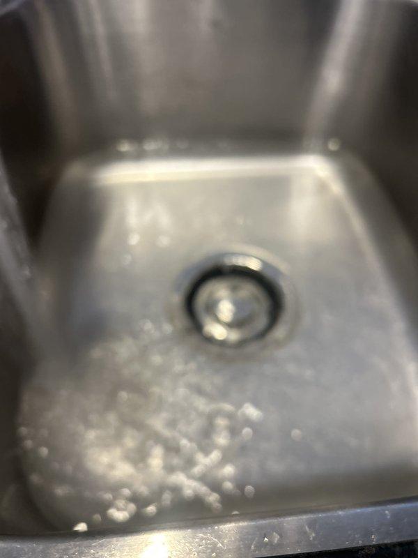 Responded to service call for garbage disposal replacement. Successfully removed existing disposal unit and installed new black cylindrical disposal unit under kitchen sink. Connected disposal to existing drain assembly with proper gasket seal and secured all chrome plumbing connections. Verified proper mounting, tested unit operation, and confirmed no leaks at drain or discharge connections. Protected work area with drop cloth and left installation clean and functional.