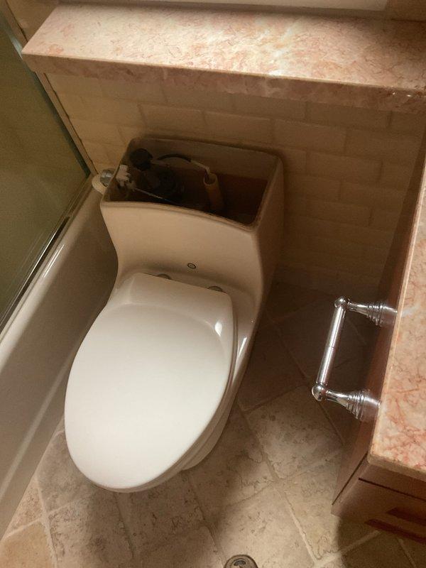 Responded to service call for TOTO toilet inspection and maintenance. Removed tank lid to assess internal flush mechanism components. Inspected flush valve assembly with red flapper seal, verified proper operation of fill valve and float mechanism, and checked for any signs of wear or leakage. All internal components found to be functioning within normal parameters. Tank interior examined for mineral buildup or deterioration. Reinstalled tank lid and confirmed toilet operational. Documented existing conditions with photographs for service records.