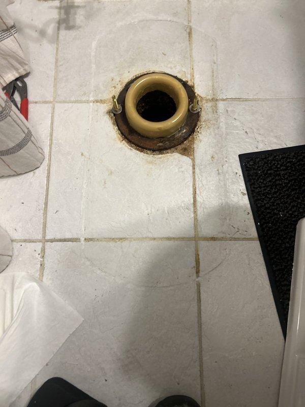 Responded to toilet leak causing water damage to downstairs condo unit in 50-year-old building. Upon inspection, identified deteriorated wax ring seal at toilet base allowing water to seep through floor assembly. Removed toilet, scraped old wax ring, inspected flange for damage, and installed new wax ring seal. Reinstalled toilet with proper alignment, tightened closet bolts to manufacturer specifications, and tested for leaks. Verified floor drain in bathroom showed signs of age-related staining but remained functional. Advised monitoring downstairs unit for further moisture intrusion and recommended follow-up inspection if leaking persists.