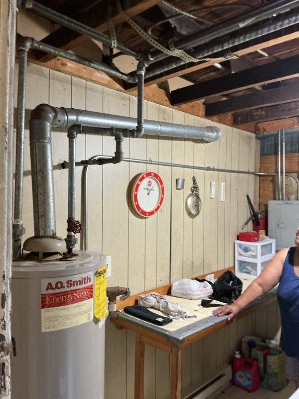 # Tanked Water Heater Leak Repair

Responded to service call for water heater leaking from top connections in 50+ year old residential property. Upon inspection, identified active leak at cold water inlet connection on A.O. Smith Energy Saver tank-style water heater located in basement utility area. Leak originated from deteriorated dielectric union and corroded nipple connection at top of tank.

Shut off main water supply and drained water heater tank to relieve pressure. Disconnected cold water supply line and removed failed dielectric union. Inspected tank inlet threads for damage and confirmed integrity. Replaced corroded steel nipple and installed new brass dielectric union with proper Teflon tape and pipe dope application to ensure watertight seal.

Reconnected cold water supply line using existing galvanized and copper piping configuration. Verified all connections at top of tank including hot water outlet, temperature and pressure relief valve, and gas supply line for any addit