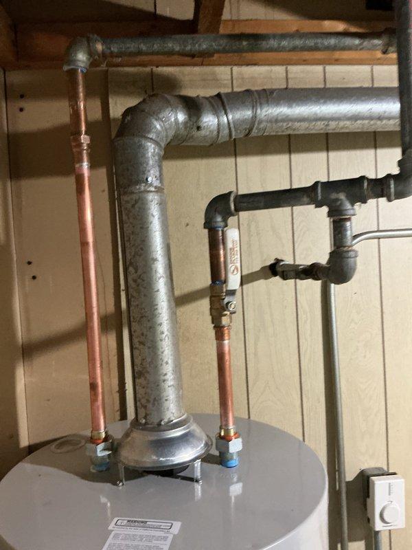 # Tanked Water Heater Leak Repair

Responded to service call for water heater leaking from top connections in 50+ year old residential property. Upon inspection, identified active leak at cold water inlet connection on A.O. Smith Energy Saver tank-style water heater located in basement utility area. Leak originated from deteriorated dielectric union and corroded nipple connection at top of tank.

Shut off main water supply and drained water heater tank to relieve pressure. Disconnected cold water supply line and removed failed dielectric union. Inspected tank inlet threads for damage and confirmed integrity. Replaced corroded steel nipple and installed new brass dielectric union with proper Teflon tape and pipe dope application to ensure watertight seal.

Reconnected cold water supply line using existing galvanized and copper piping configuration. Verified all connections at top of tank including hot water outlet, temperature and pressure relief valve, and gas supply line for any addit