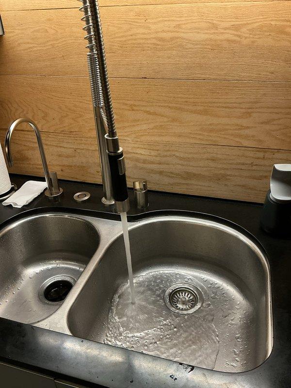 Responded to service call for low water pressure at kitchen sink with professional-style pull-down spray faucet. Upon inspection, tested water flow at the faucet spray head and observed reduced pressure output. Examined the undermount double-bowl stainless steel sink installation and inspected all visible plumbing connections beneath the sink, including supply lines, shut-off valves, and drain assemblies. Checked for potential obstructions in the aerator and spray head, verified proper function of the pull-down mechanism, and assessed supply line condition and valve operation to identify the source of pressure reduction.