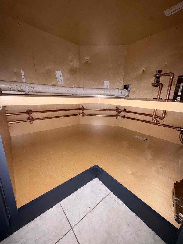Conducted site assessment and created detailed branch job summary diagram for kitchen plumbing and HVAC modifications. Measurements documented include 51" to sink center, 45" to dishwasher center, and 3' gas radiant panel placement. Proposed removal and replacement of existing window tray to accommodate new ductwork installation for heat output through wall per customer specifications. Inspected existing copper piping system and PVC conduit in utility area, noting proper bracket mounting and valve placements. Project will resume upon completion of cabinet installation to finalize plumbing rough-in connections for sink and dishwasher centers.