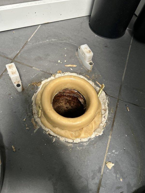 Responded to water leak investigation following ceiling access by litigation company. Upon inspection, identified compromised toilet flange with significant corrosion around drain opening and deteriorated wax ring seal causing water intrusion. Documented existing conditions showing rust damage to flange assembly, degraded sealing materials, and residue on surrounding tile floor requiring remediation and proper reinstallation of toilet fixture.