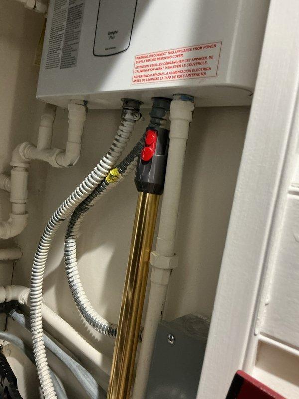 Performed reverse osmosis system maintenance by accessing the water treatment equipment and replacing the RO filter cartridge. Inspected system components including the storage tank, brass filter housing with black valve assembly, and associated plumbing connections to ensure proper operation and verify no leaks were present after filter replacement.