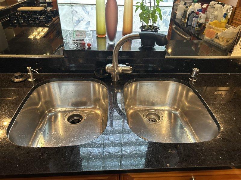 Performed smoke test on kitchen drain system to identify source of persistent musty odor in 25-year-old condo. Introduced non-toxic smoke into plumbing system through cleanout access points and monitored all drains, vents, and trap connections under double-basin sink with garbage disposal. Smoke test revealed no visible leaks or breaches in drain lines, P-traps, or vent stack connections, indicating proper seal integrity throughout the drainage system. Inspected cabinet area beneath sink during testing, verifying all connections at disposal unit and drain assemblies remained sealed. Based on test results showing no compromised plumbing components, advised that odor source may be related to biofilm buildup within drain lines or potential issues with building vent system beyond unit's interior plumbing. Recommended enzymatic drain treatment and possible consultation with building management regarding common vent stack condition.