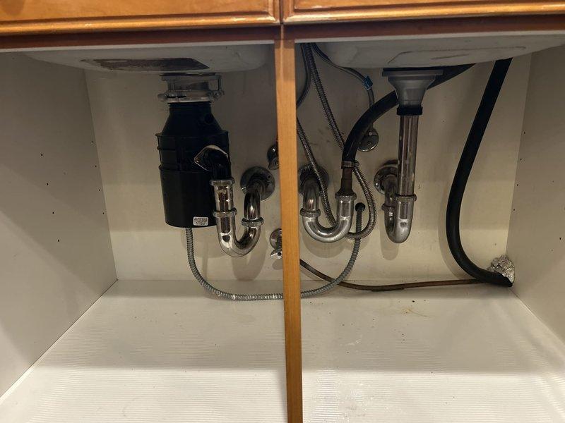 Performed smoke test on kitchen drain system to identify source of persistent musty odor in 25-year-old condo. Introduced non-toxic smoke into plumbing system through cleanout access points and monitored all drains, vents, and trap connections under double-basin sink with garbage disposal. Smoke test revealed no visible leaks or breaches in drain lines, P-traps, or vent stack connections, indicating proper seal integrity throughout the drainage system. Inspected cabinet area beneath sink during testing, verifying all connections at disposal unit and drain assemblies remained sealed. Based on test results showing no compromised plumbing components, advised that odor source may be related to biofilm buildup within drain lines or potential issues with building vent system beyond unit's interior plumbing. Recommended enzymatic drain treatment and possible consultation with building management regarding common vent stack condition.