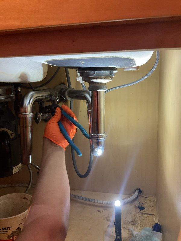 Performed kitchen sink drain repair and inspection underneath the cabinet. Accessed the P-trap assembly and chrome drain tailpiece to diagnose and address drainage concerns. Completed necessary adjustments to the plumbing fixtures and verified proper operation of the sink drain system.