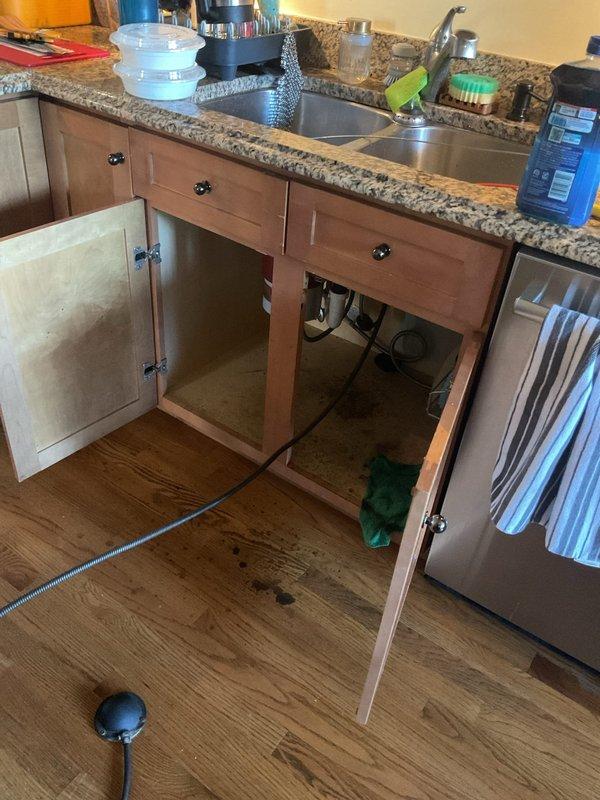 Responded to kitchen sink backup issue and performed main drain cleanout service. Accessed drain system through under-sink plumbing and exterior cleanout access point, successfully cleared blockage and restored proper drainage. Utilized professional drain cleaning equipment to remove obstruction from main drain line, tested system operation, and confirmed full resolution of backup condition.