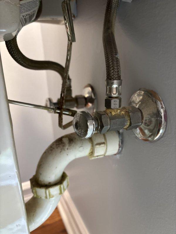 Responded to service call for two leaky Moen faucets in master bathroom and powder room. Inspected under-sink plumbing in both locations, examining P-trap assemblies, supply lines, and shut-off valves for proper installation and potential leak sources. Photographed existing plumbing configuration showing white PVC drain assemblies with some discoloration, flexible braided supply lines, and chrome shut-off valves. Also evaluated laundry area for reported sewer odor issues occurring during heavy rainfall, likely related to drain trap seal failure or venting problems that require further diagnostic assessment.