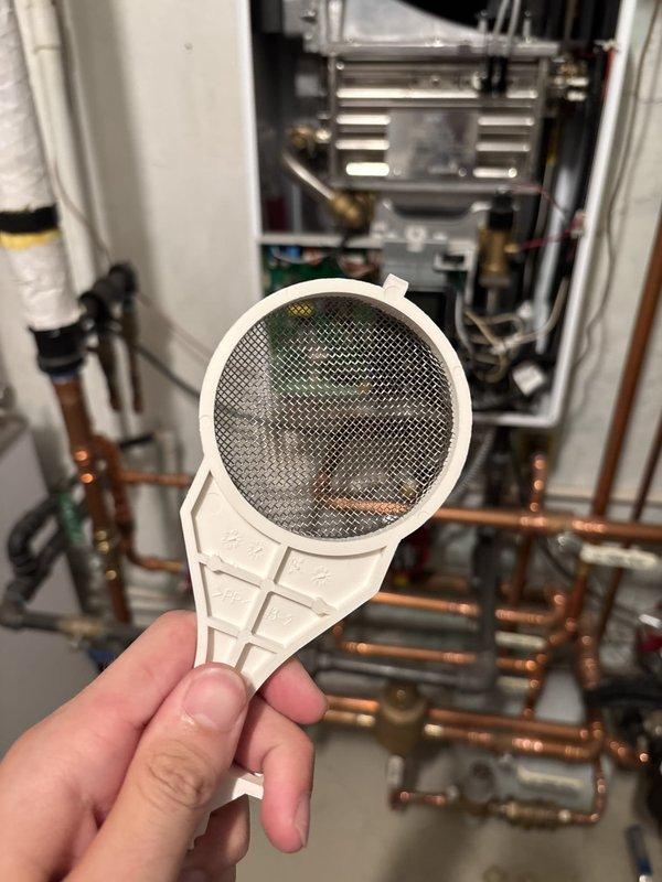 Completed routine boiler inspection on century-old residential heating system. Removed and examined intake air filter and water strainer, both showing accumulated sediment and debris consistent with system age and usage. Filters were cleaned and reinstalled to ensure proper airflow and water flow through the unit. Inspected copper supply lines, gas connections, and circuit board for signs of wear, corrosion, or malfunction—all components found to be functioning within normal parameters with no immediate service needs identified.
