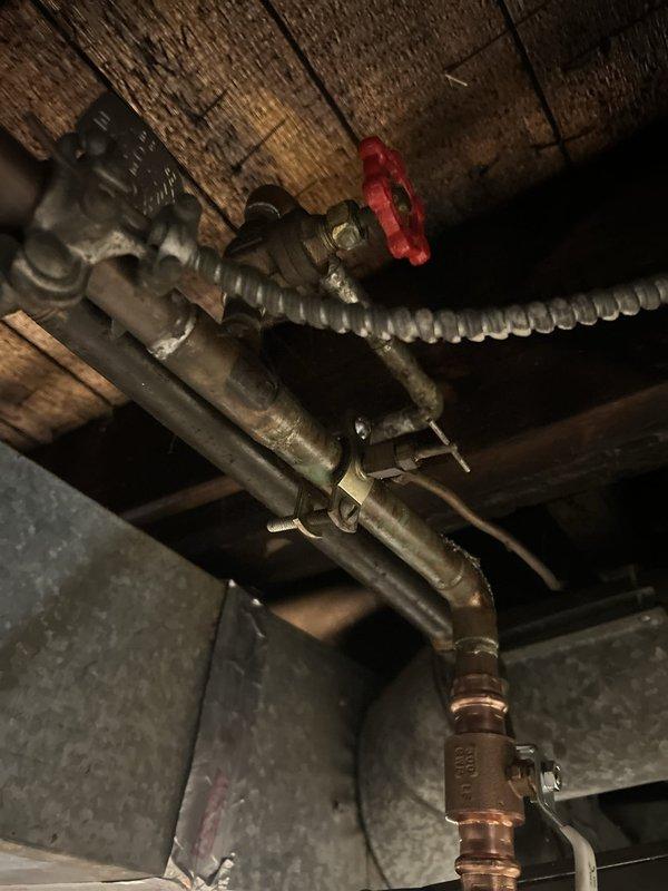 Responded to service call for water heater leaking at base. Upon inspection, found GE brand tanked water heater installed in 2010 showing active leak at bottom of unit. Documented existing plumbing configuration including red-handled shut-off valve, metal supply lines, and flexible connectors mounted to floor joists. Photographed current installation setup and leak condition. Provided estimate for water heater replacement due to tank failure, as leaks at base typically indicate internal tank corrosion that cannot be repaired.