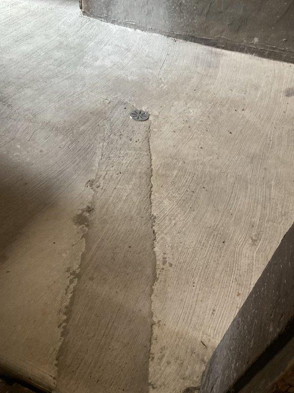 Responded to emergency plumbing call for failed ejector pump system in century-old residential property. Upon arrival, identified uncapped discharge pipe in basement as active source of water release, which had previously caused flooding. Inspected recently installed ejector pump (2024) and associated plumbing infrastructure, including vertical PVC discharge piping with multiple connection joints and coupling assembly. Documented existing conditions showing exposed brick foundation walls, concrete floor with evidence of prior water damage and staining, and compromised drainage system. Assessed structural elements of basement utility area and photographed failed pump installation, uncapped pipe terminus, and floor drain assembly to document extent of water damage and system failure. Provided technical evaluation of pump malfunction and recommended corrective action plan to address immediate water discharge issue and prevent future flooding events.