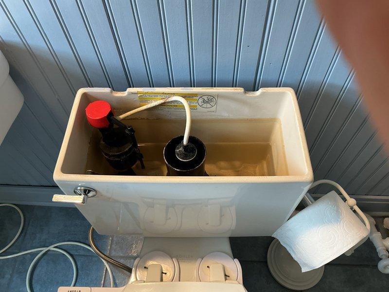 Responded to multiple bathroom plumbing repairs including a running toilet, malfunctioning shower diverters, sink drain pipe leaks, and a tub drain clog. Inspected toilet tank components and identified flush valve assembly issues causing continuous water flow. Addressed tub drainage problem and verified water flow from spout during testing. Photographed toilet tank interior showing flush mechanism and refill tube configuration, as well as bathtub with visible water discharge from chrome spout fixture. Completed necessary adjustments and repairs to restore proper function to affected fixtures throughout the residence.
