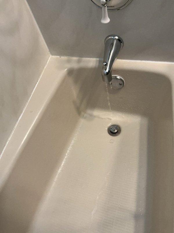 Responded to multiple bathroom plumbing repairs including a running toilet, malfunctioning shower diverters, sink drain pipe leaks, and a tub drain clog. Inspected toilet tank components and identified flush valve assembly issues causing continuous water flow. Addressed tub drainage problem and verified water flow from spout during testing. Photographed toilet tank interior showing flush mechanism and refill tube configuration, as well as bathtub with visible water discharge from chrome spout fixture. Completed necessary adjustments and repairs to restore proper function to affected fixtures throughout the residence.