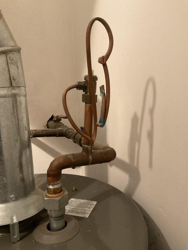 Completed water heater service during scheduled building shutdown. Inspected existing water heater installation including copper piping system with pressure relief configuration and circulation loops. Evaluated HVAC system connections, condensate drain pan with active moisture accumulation, and associated copper pipe connections at ceiling level. Documented equipment condition showing age-related copper oxidation and patina on piping throughout the system.