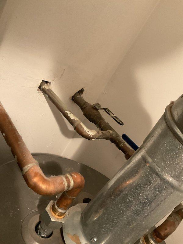 Completed water heater service during scheduled building shutdown. Inspected existing water heater installation including copper piping system with pressure relief configuration and circulation loops. Evaluated HVAC system connections, condensate drain pan with active moisture accumulation, and associated copper pipe connections at ceiling level. Documented equipment condition showing age-related copper oxidation and patina on piping throughout the system.