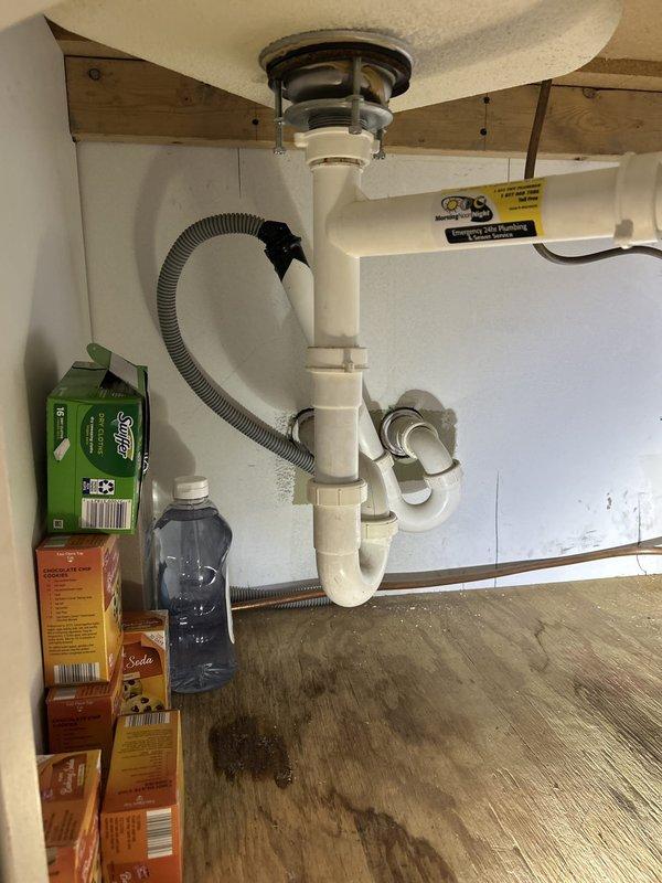 Responded to service call for kitchen plumbing issues involving a malfunctioning faucet and stuck water shutoff valve. Upon inspection, found existing kitchen faucet was improperly installed backwards, exhibiting active leaks and general disrepair requiring full replacement. Assessed under-sink plumbing configuration featuring double-basin setup with white PVC P-trap assemblies and braided stainless steel supply lines connected to chrome shutoff valves mounted on cabinet back wall. Evaluated stuck water valve that would not close properly, determining it required careful assessment to avoid forcing and potentially damaging the valve mechanism. Provided estimate for replacement of kitchen faucet with customer-supplied fixture and repair or replacement of compromised shutoff valve as needed to restore proper water control functionality.