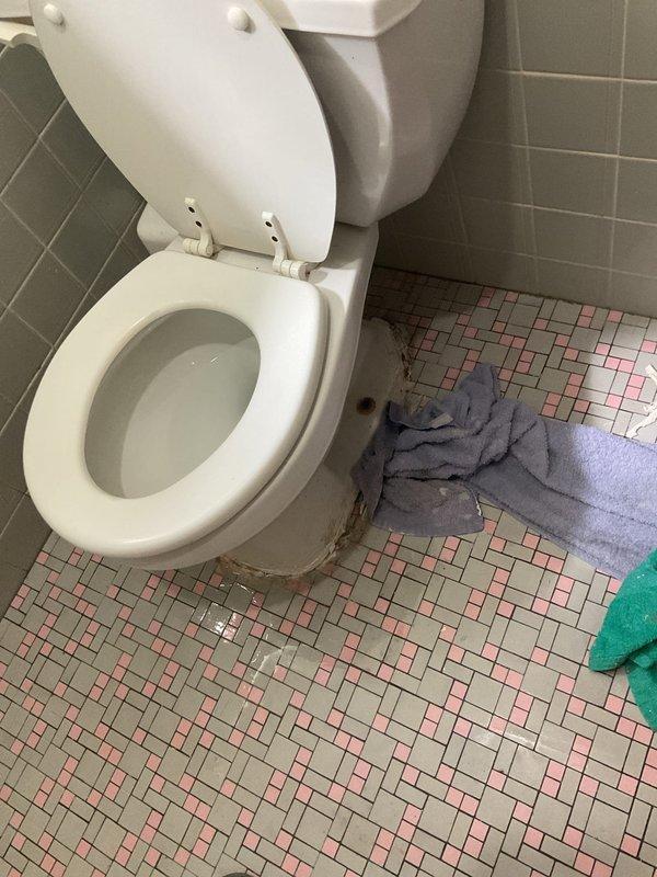 Responded to report of toilet leaking at base. Upon inspection, discovered significant corrosion and rust buildup on floor drain fixture adjacent to toilet, with deterioration extending to surrounding grout and tile surfaces. Removed toilet to access and assess leak source at base seal. Replaced wax ring and toilet mounting bolts. Inspected toilet flange for damage and verified proper seating. Reinstalled toilet, ensuring proper alignment and secure mounting to prevent future leaks. Tested for leaks by flushing multiple times and confirmed no water discharge at base. Advised regarding corroded floor drain fixture requiring future attention to prevent further deterioration of bathroom flooring.