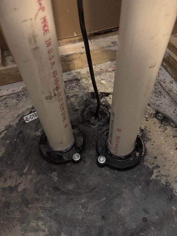 Responded to complaint of sewer gas odor detected in first and second floor bathrooms. Performed diagnostic inspection and identified multiple plumbing vents penetrating concrete floor in basement area. Documented existing PVC vent pipe installations with proper floor penetration seals and rubber coupling boots. All vent pipes appeared properly installed with manufacturer specifications visible and appropriate floor sealing mechanisms in place. Recommended monitoring situation and further smoke testing if odors persist to pinpoint exact source of sewer gas infiltration.