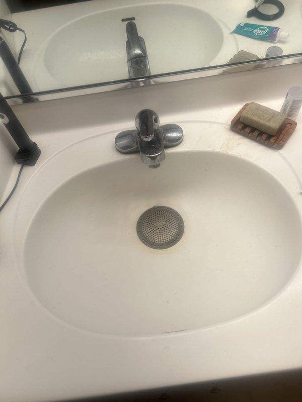 Provided estimate for removal and replacement of kitchen sink and installation of customer-supplied bathroom faucets in dual-handle chrome configuration. Additionally assessed gas leak located near water heater requiring immediate attention for safety compliance. Documented existing fixtures including double-basin stainless steel kitchen sink with chrome faucet and white bathroom vanity with integrated oval basin and dual-handle controls.