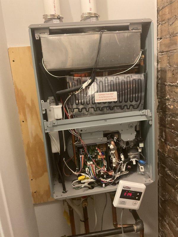 Responded to no hot water complaint on 2.5-year-old wall-mounted tankless water heater unit. Upon inspection, accessed internal components by removing front panel to diagnose system failure. Examined heat exchanger assembly, burner components, electrical control boards, wiring connections, and digital display panel. Evaluated gas supply lines, copper water piping connections, and condensate drainage system for proper operation. Restored hot water functionality to the unit.