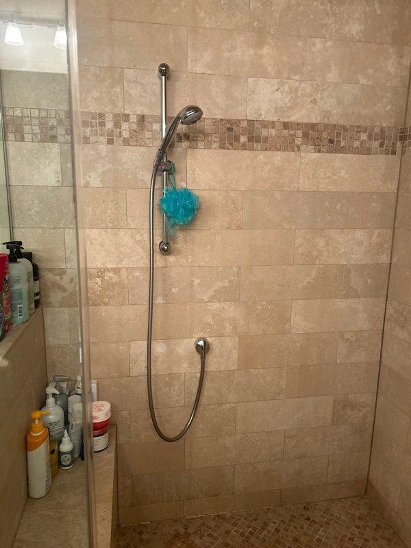Responded to service call for shower with no cold water supply. Inspected existing shower system with multiple chrome control valves and handheld showerhead on slide bar. Diagnosed temperature control issue affecting cold water delivery to fixtures. Documented existing tile shower enclosure with travertine-style tile walls, mosaic border detail, and dual showerhead configuration. Provided estimate for steam shower installation as requested.