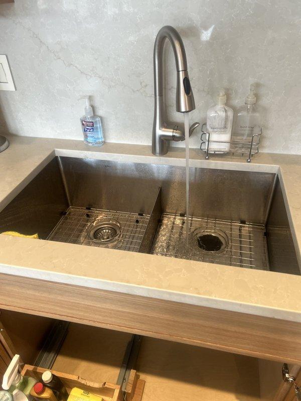 Responded to kitchen sink leak complaint and performed comprehensive inspection of undermount double-basin sink assembly and associated plumbing components. Upon examination, identified potential leak source in P-trap connection and supply line fittings beneath sink. Inspected InSinkErator garbage disposal unit, drain connections, flexible braided supply lines, and corrugated drainage hose for signs of moisture or active leaking. Verified all plumbing connections were properly secured and tested system under operating conditions with water flow to confirm leak resolution. Ensured proper drainage function and confirmed no moisture present on cabinet floor or surrounding areas following repairs.