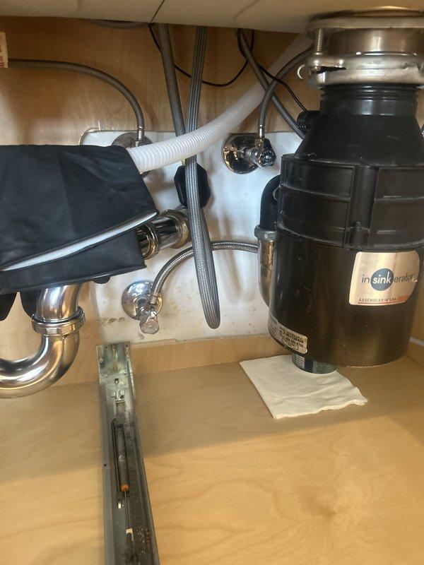 Responded to kitchen sink leak complaint and performed comprehensive inspection of undermount double-basin sink assembly and associated plumbing components. Upon examination, identified potential leak source in P-trap connection and supply line fittings beneath sink. Inspected InSinkErator garbage disposal unit, drain connections, flexible braided supply lines, and corrugated drainage hose for signs of moisture or active leaking. Verified all plumbing connections were properly secured and tested system under operating conditions with water flow to confirm leak resolution. Ensured proper drainage function and confirmed no moisture present on cabinet floor or surrounding areas following repairs.