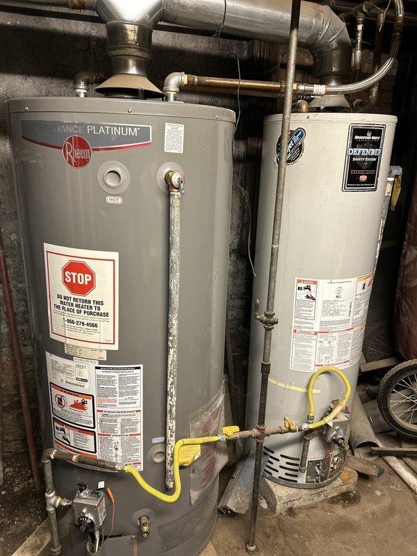 Completed initial assessment and preparation for gas pipe work installation at property with two existing water heaters (Rheem Performance Platinum and Bradford White Defender Safety System models). Observed significant infrastructure concerns including corroded gas piping connections with visible rust and deterioration on metal components, along with overhead water damage and peeling paint on ceiling surfaces indicating moisture intrusion issues. Yellow flexible gas lines currently connected to both water heater units. All necessary materials for gas pipe work have been delivered to site and staged for installation. Work scheduled to resume next business day to proceed with gas piping replacement and system upgrades. Documented existing conditions through photographic evidence showing current water heater installations, deteriorated piping assemblies, and compromised ceiling conditions in utility area.